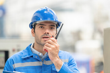 Close-up shot of white american male engineer Was talking via radio communication to a meeting in a large plastic and steel industry. There is beautiful bokeh in the background. © Nutchapong Wuttisak