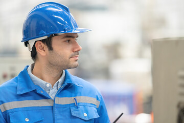 Close-up side view of a white-skinned American engineer looking smart in a large plastic and steel...