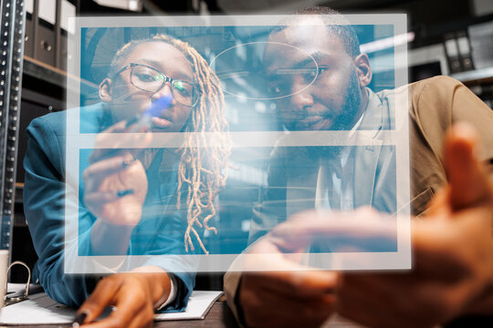 Private detective analyzing hologram in evidence room, checking artificial intelligence holographic image. Team of inspectors working with augmented reality, looking at evidence photos.