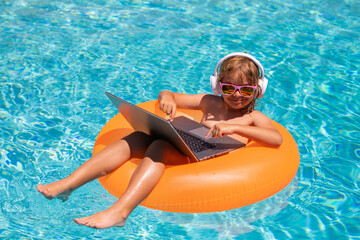 Work outside concept. Child working on laptop computer at poolside swimming pool. Summer online technology. Traveler relaxing on tropical sea beach in summer holidays vacation. - obrazy, fototapety, plakaty