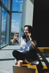 Positive woman with coffee, working video call on laptop with webcams for communication, happy with help woman watching comedy video on netbook in free time sitting in cafe