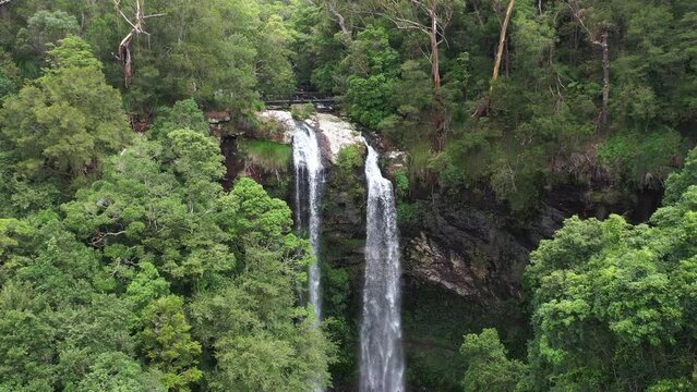 Aerial fly back out from Twin Falls through the rainforest, to reveal the entire falls and pool below. Springbrook National Park, Gold Coast hinterland