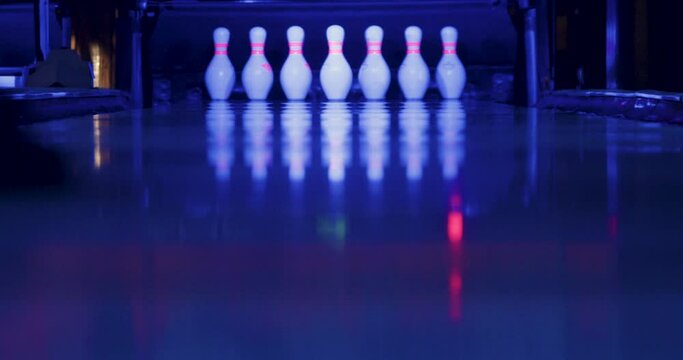 The video captures the moment when the man successfully throws the ball in bowling, causing all the pins to fall except for one.