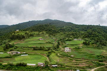 A typical Bhutanese hamlet, with traditional houses surrounded by agriculture fields, which are in turn bordered by forest.