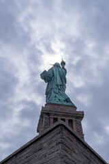 Fototapeta na wymiar Back of the statue of liberty against a cloudy sky