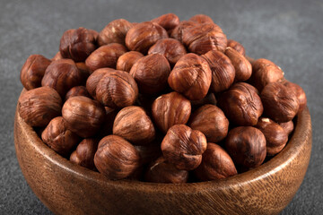 View of a bowl full of hazelnuts on a black background
