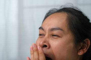 Tired woman yawning covering her mouth with her hands wanting to rest. Portrait of Asian woman with...