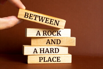 Wooden blocks with words 'Between a rock and a hard place'.