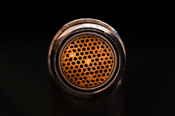 Plaque and corrosion on the diffuser aerator in the faucet close-up. Limescale on the faucet, on a black background