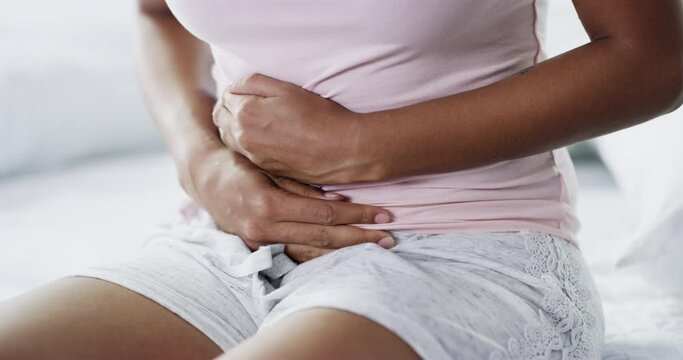 Stomach pain, cramps and closeup of woman in bedroom for menstruation, pms and sickness. Problem, digestion and period with person and abdomen illness at home for virus, indigestion and constipation