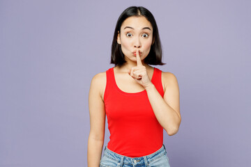 Young secret woman of Asian ethnicity wear casual clothes red tank shirt say hush be quiet with finger on lips shhh gesture isolated on plain pastel light purple background studio. Lifestyle concept.