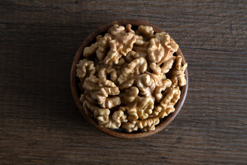 Bowl full of peeled walnuts on a wooden background,overhead view
