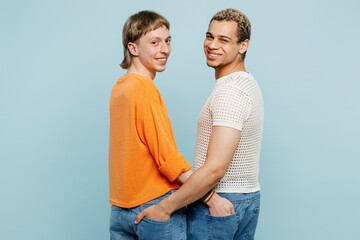 Side view young happy couple two gay men wear casual clothes together put hands in pocket isolated on pastel plain light blue color background studio portrait. Pride day june month love LGBTQ concept.