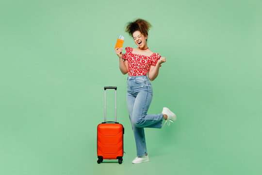 Traveler woman wears summer casual clothes hold suitcase passport ticket isolated on plain green color background Tourist travel abroad in free spare time rest getaway. Air flight trip journey concept