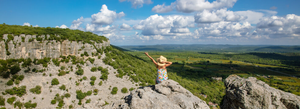 Woman with dress sitting on a mountain peak looking at view of languedoc landscape panorama- tourism in France concept