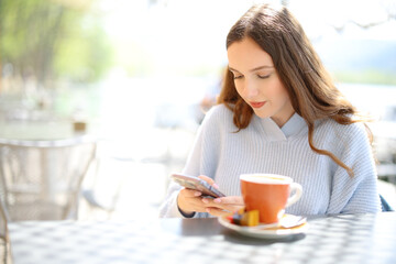 Woman using cell phone in a coffee shop terrace