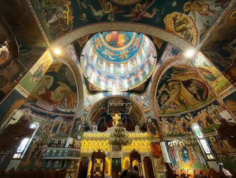 Perspective looking up to the detailed underside of the dome in an orthodox church with beautiful iconographic paintings on the dome and altar in Titan,  Bucharest, Romania.