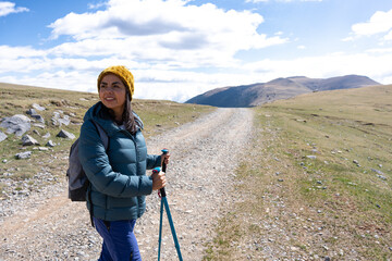 Latina woman observing the landscape and the road while resting a day of trekking in the mountains.