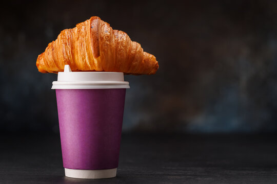 Aromatic coffee in a paper cup paired with a flaky croissant