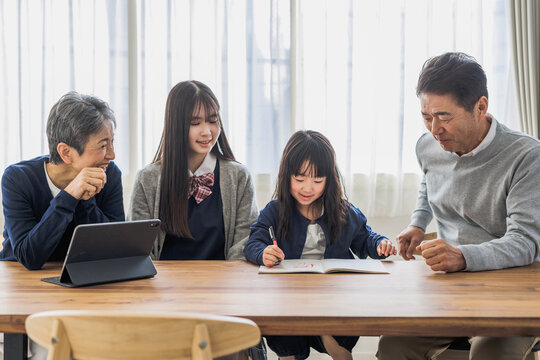 勉強する孫を見守る日本人シニア夫婦