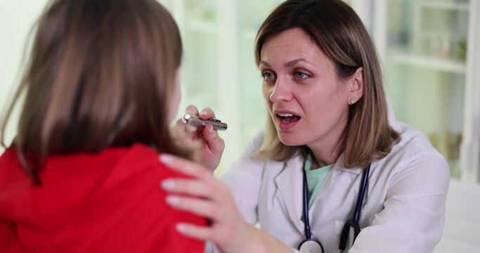 Otorhinolaryngologist examines girl with sore throat. Pharyngitis in children causes symptoms and treatment