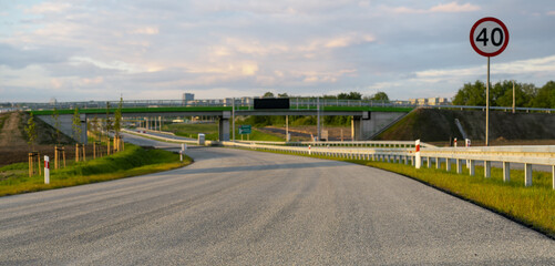 Newly constructed highway,asphalt,guardrails.In the background spring landscape - obrazy, fototapety, plakaty