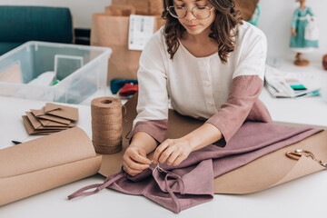 Fashion designer tying price tag on dress at workshop