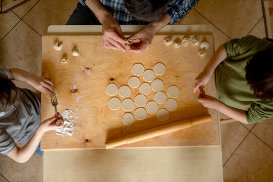 Father teaching children to make dumplings on table at home