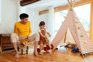Mother and son spending leisure time playing with tricycles at home