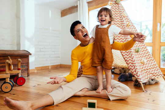 Happy mother playing with son in living room at home