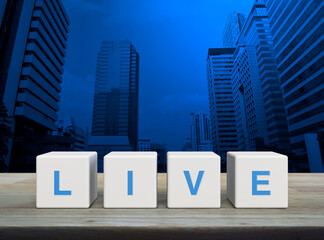 Live letter on white block cubes on wooden table over modern office city tower and skyscraper, Technology broadcasting communication concept