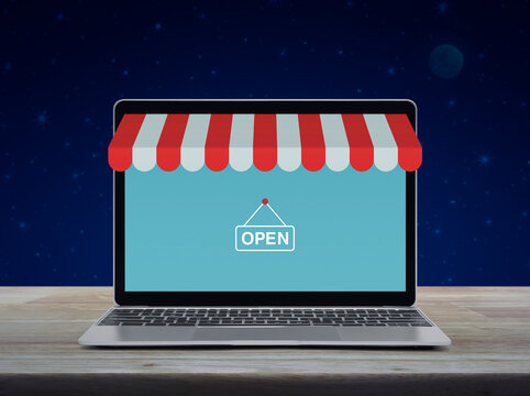 Modern laptop computer with online shopping store graphic and open sign on wooden table over fantasy night sky and moon, Business internet shop online concept