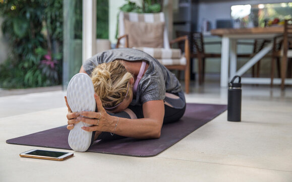 Woman practicing Janu Sirsasana on exercise mat at home