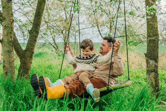 Father swinging with son in garden