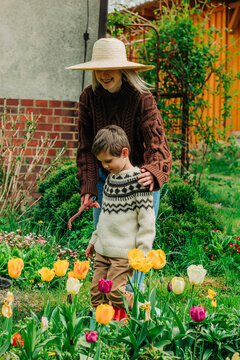 Mother and son standing near tulips in garden