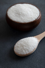Granulated sugar in bowl on black background
