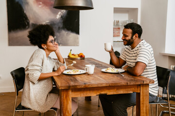 Smiling couple having lunch together while sitting in kitchen