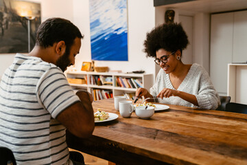 Smiling couple having lunch together while sitting in kitchen