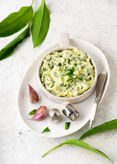 Homemade butter with fresh herbs: wild garlic leaves, lemon juice, pepper and salt in a ceramic...
