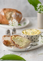 Slice of sourdough bread with homemade butter of wild garlic, ramsons flowers.  Healthy herb food concept. Selective focus.