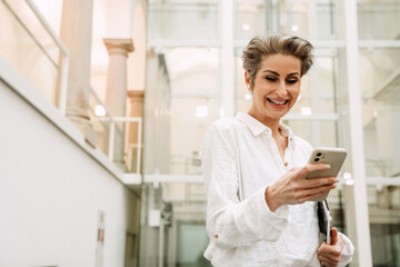 Portrait of woman art gallery manager using smartphone while standing in museum