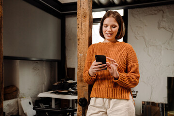 Beautiful woman using mobile phone while standing in office