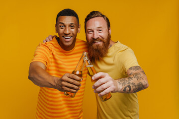Two happy men smiling at camera holding beer while standing isolated