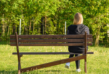 Samotna kobieta siedzi na drewnianej ławce na świeżym powietrzu  - obrazy, fototapety, plakaty