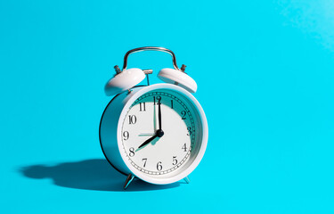 White alarm clock on a blue background isolated, close-up.