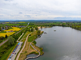 Aerial view landscape. View of the lake, paths around and fields with rapeseed. Poland, przylasek Rusiecki.