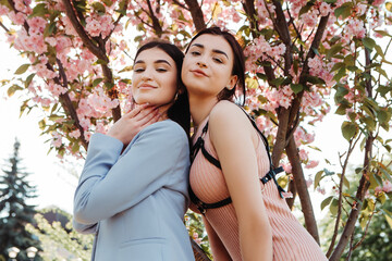 Attractive women posing near pink sakura cherry blossoms blooming flowers in the garden park in...