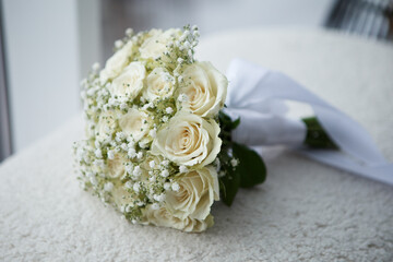 Bridal wedding bouquet lying on modern brown sofa at home photo session studio. Stunning green white flowers roses wildflowers. Engagement between two lovoer people. Image with copy space.
