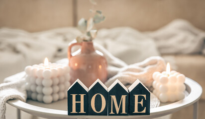 Cozy composition with decorative word home, candles and vase on blurred background.