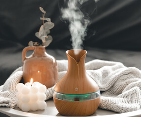 Spa composition with aroma oil diffuser lamp and candle on a blurred background.